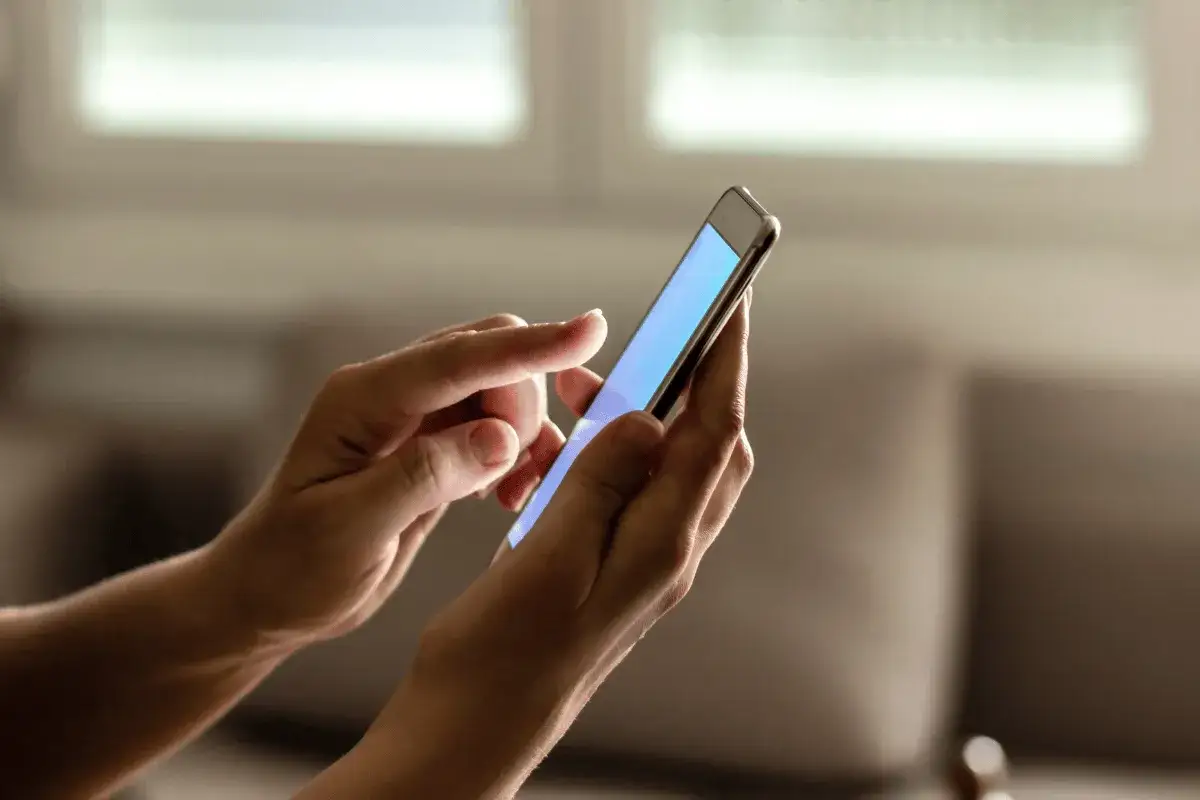 Dłonie trzymają smartfon, na którym można sprawdzić ile lat ma telefon.