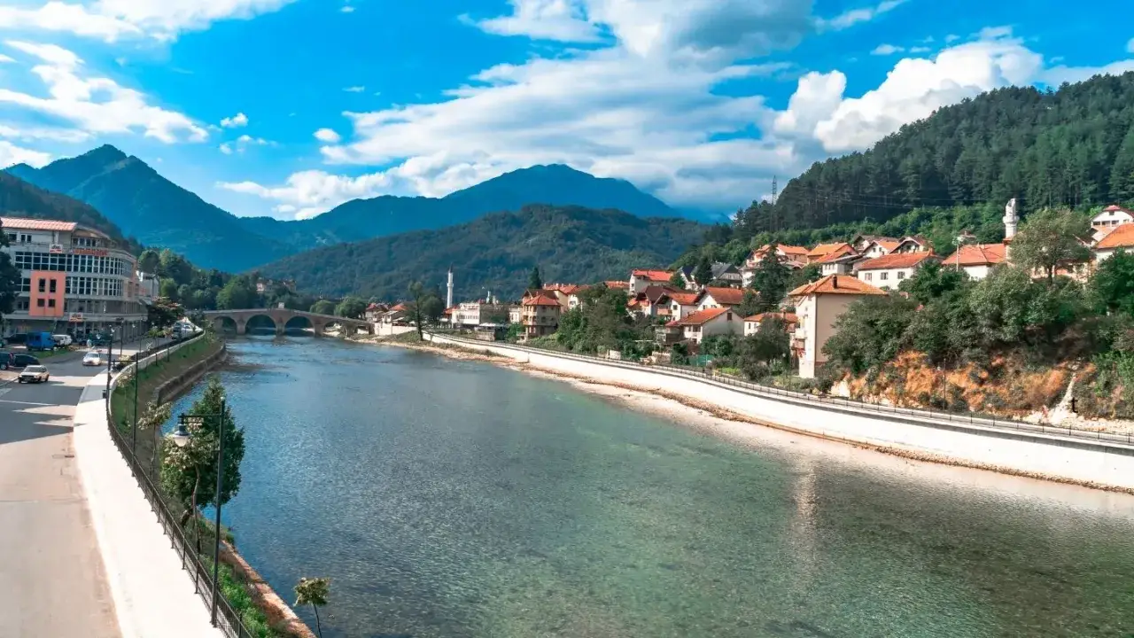 Widok na miasto z rzeką w Mostarze, z górami w tle i tradycyjną architekturą.
