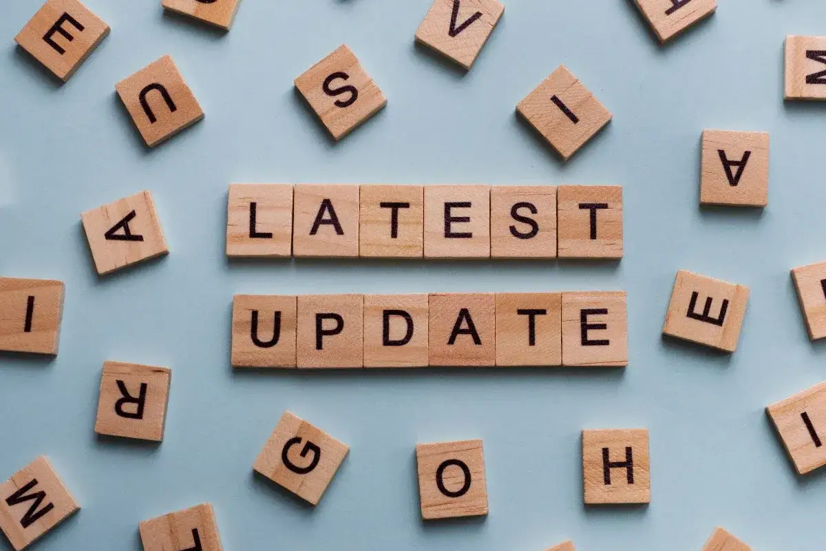 Drewniane klocki z literami tworzą napis "LATEST UPDATE". Dowiedz się, jak zaktualizować sterowniki w komputerze, aby cieszyć się najnowszymi funkcjami.