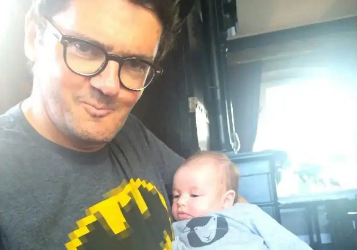 Kuba Wojewódzki z dzieckiem na rękach, w koszulce z Batmanem. Czy Kuba Wojewódzki ma dzieci? Tak, to dowód!