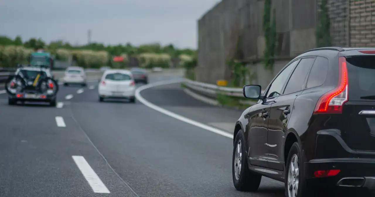 Czarny SUV na autostradzie, obok białe samochody. Pamiętaj, kiedy można wyprzedzać z prawej strony, by uniknąć korków.