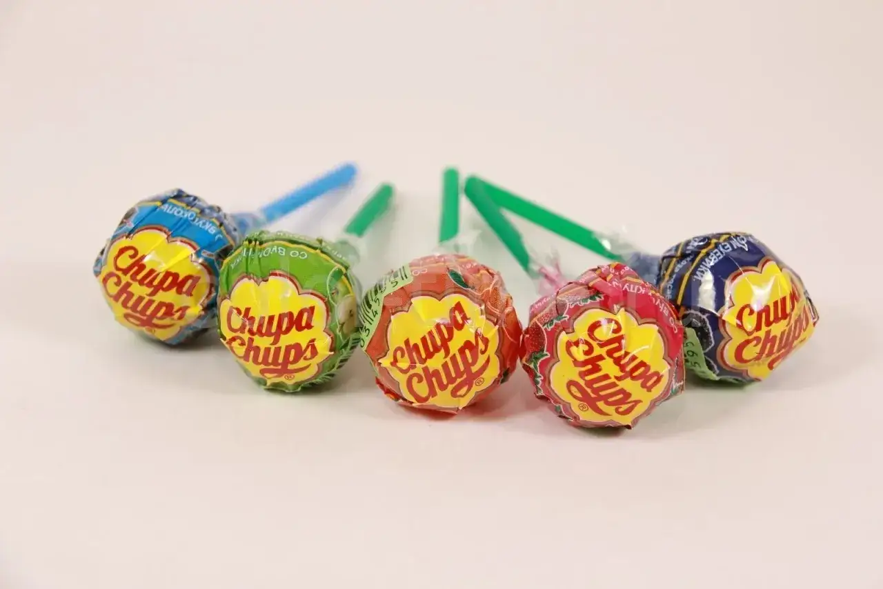 Kilka lizaków Chupa Chups w różnych kolorach i smakach na białym tle.