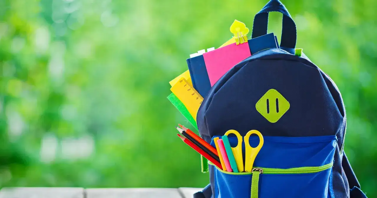 Plecak z przyborami szkolnymi: kredki, nożyczki, linijka, zeszyty. Czas zacząć naukę, gdy semestr szkolny trwa wiele tygodni.