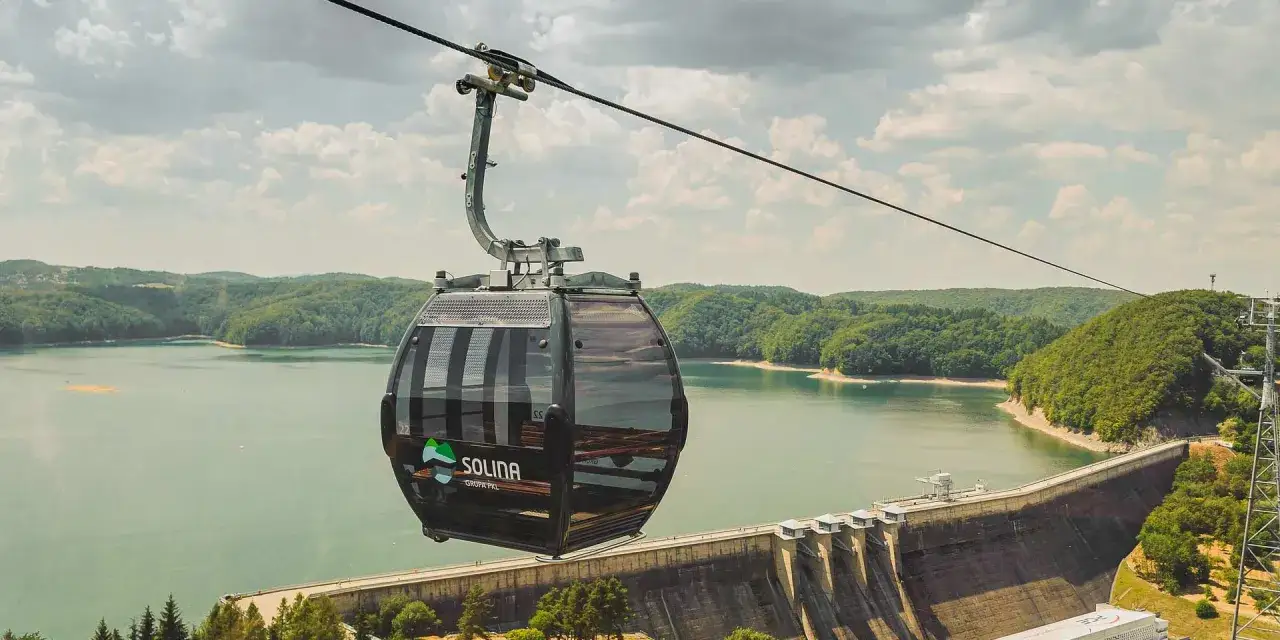 Kolejka gondolowa nad zaporą w Solinie. Widok na jezioro i lasy. To alternatywa, jak dojechać nad Solinę pociągiem i podziwiać widoki.