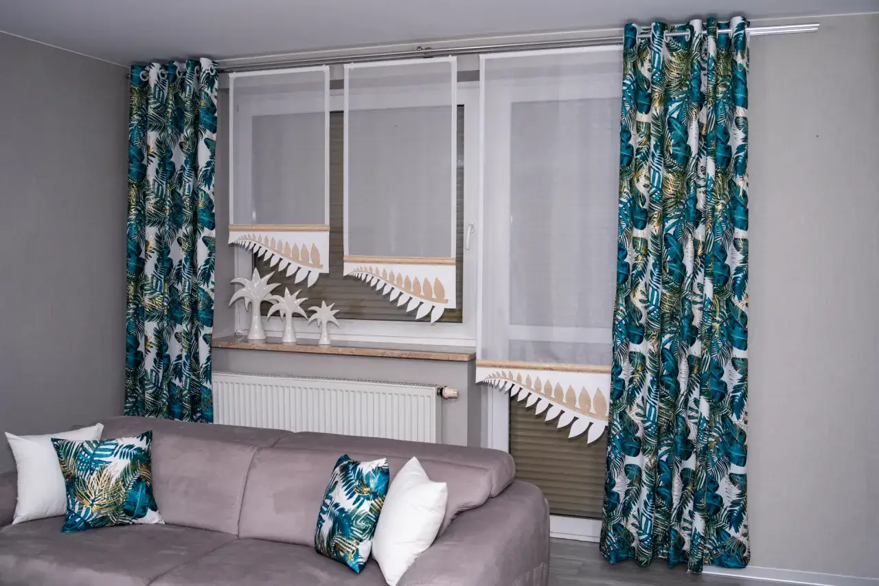 Nowoczesny karnisz na okno balkonowe z zasłonami w liście palmowe.