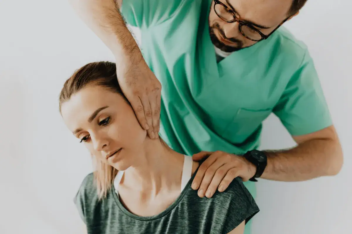 Fizjoterapeuta wykonuje masaż szyi pacjentki.