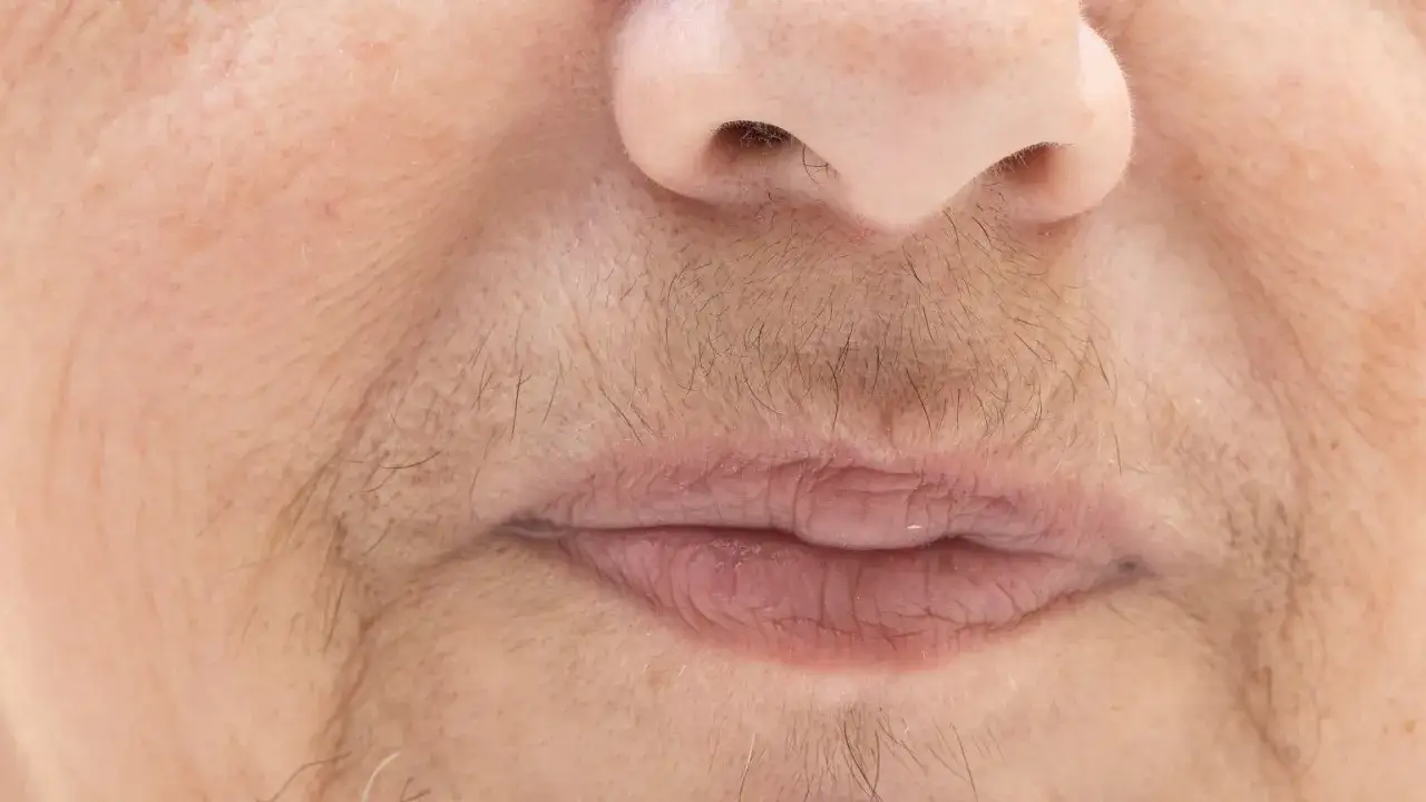 Zbliżenie na usta i nos kobiety, widoczne włoski na twarzy, sugerujące golenie twarzy u kobiet.