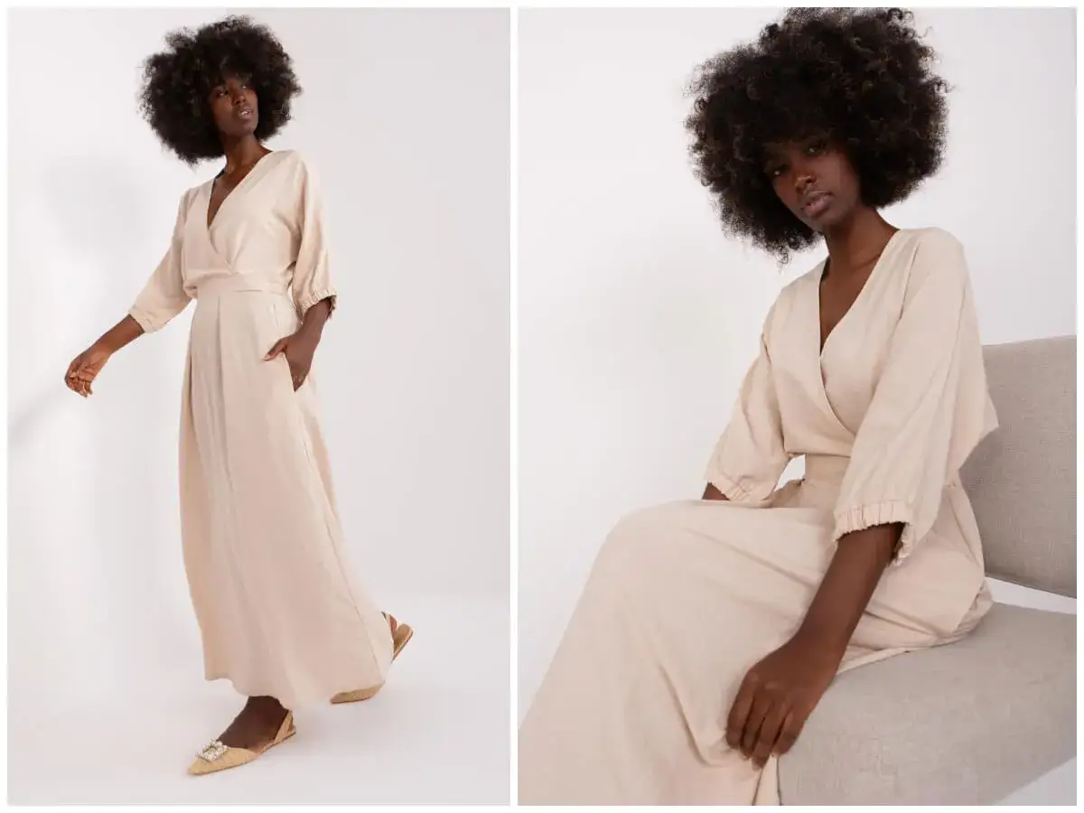 Kobieta w beżowej sukience empire, która podkreśla talię. Sukienka ma dekolt kopertowy i luźne rękawy.