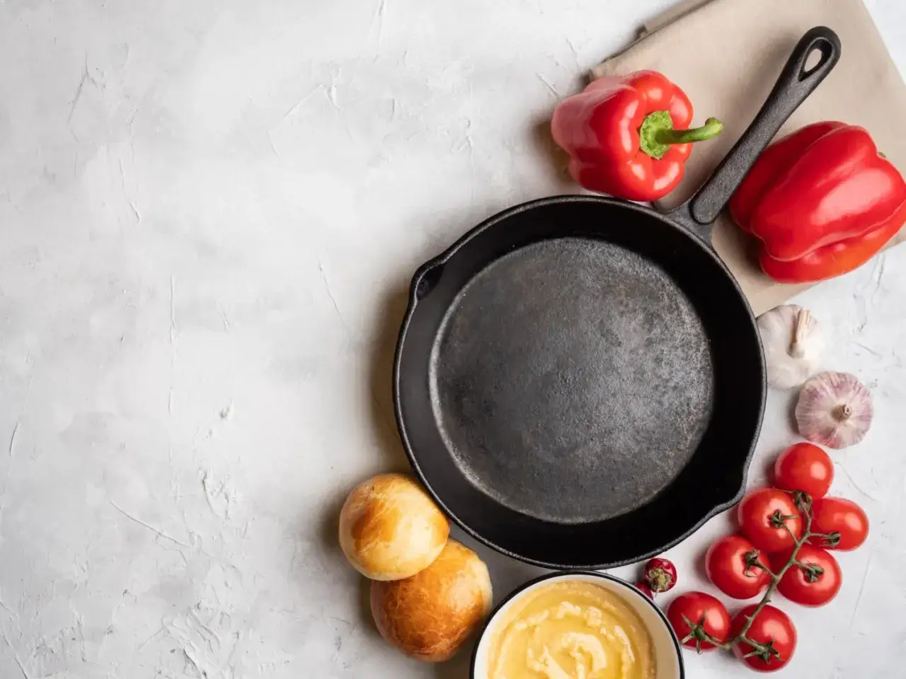 Żeliwna patelnia, papryki, pomidorki, czosnek i bułeczki. Zastanawiasz się, jakich patelni należy unikać? Ta wygląda na solidną.