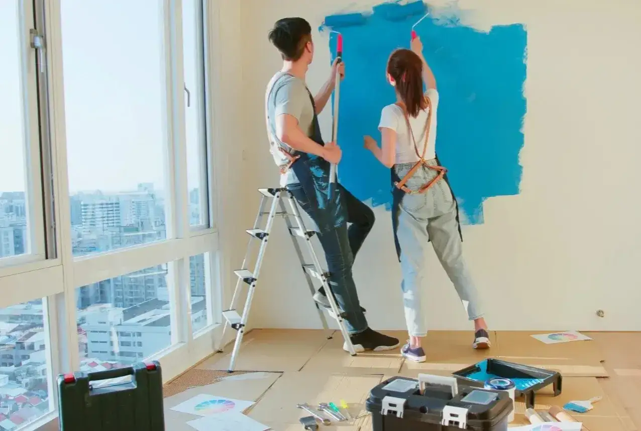Para malować farbą dekoracyjną jak nakładać, para maluje ścianę na niebiesko.