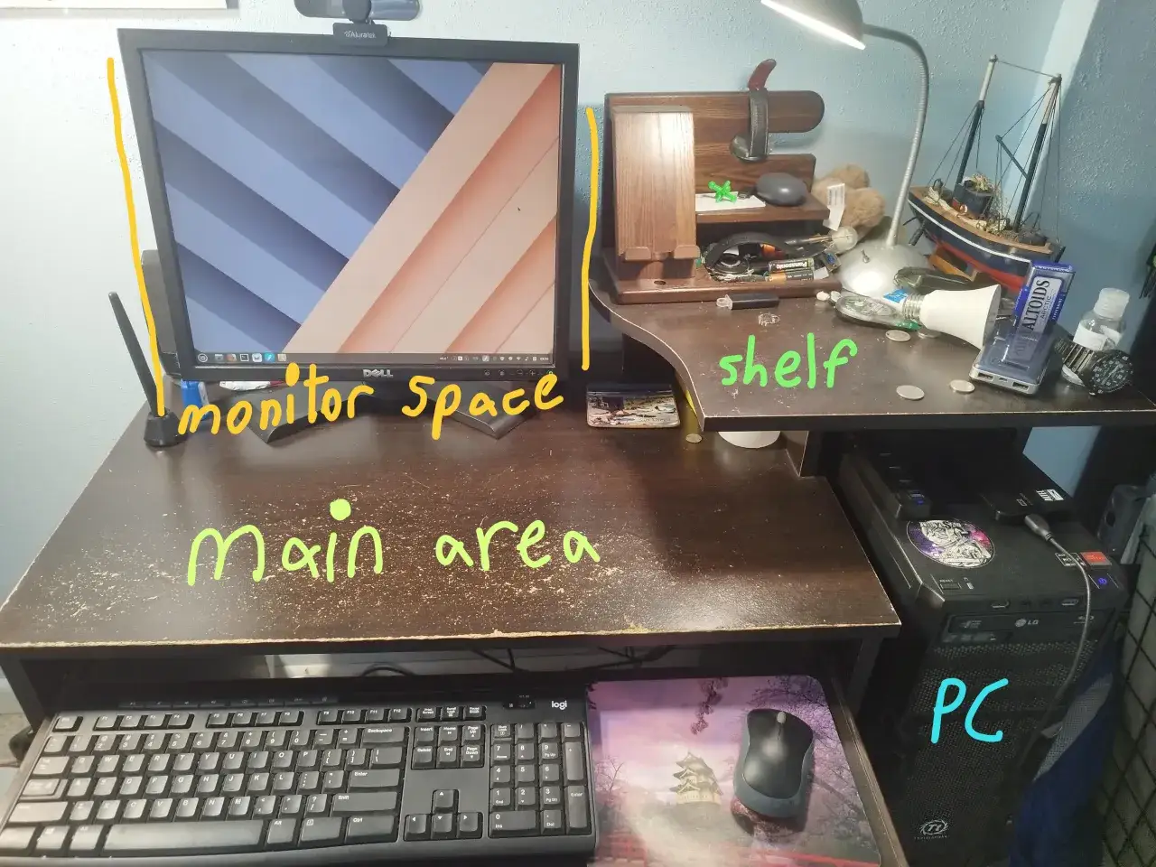 Biurko z monitorem 21 cali, PC, klawiaturą i półką. Na półce stoją ozdoby i drobne przedmioty.