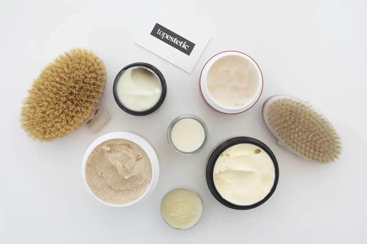Kremy i peelingi do ciała, szczotki do masażu i wizytówka z napisem "topestetic". Wiele z tych produktów zawiera phenoxyethanol w kosmetykach, zapewniając ich trwałość.