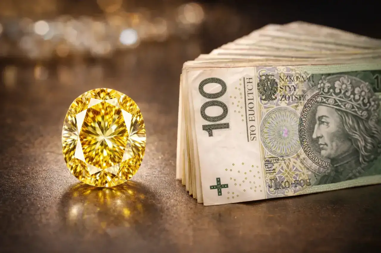 Olśniewający, duży, żółty diament lśni obok stosu banknotów 100-złotowych.