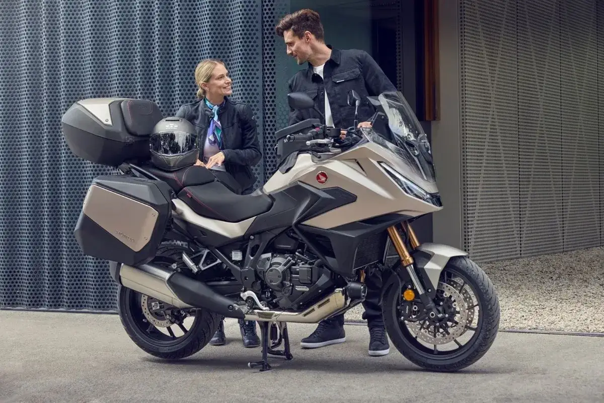 Para zwiedzająca motocykle z automatyczną skrzynią biegów. Nowoczesny turystyczny motocykl Honda z kuframi.
