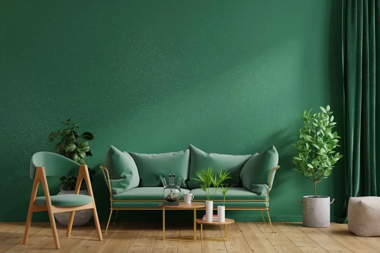 Zielona ściana z brokatem, sofa, krzesło i rośliny tworzą przytulne wnętrze. Dowiedz się, jak nałożyć brokat na ścianę, by uzyskać taki efekt.