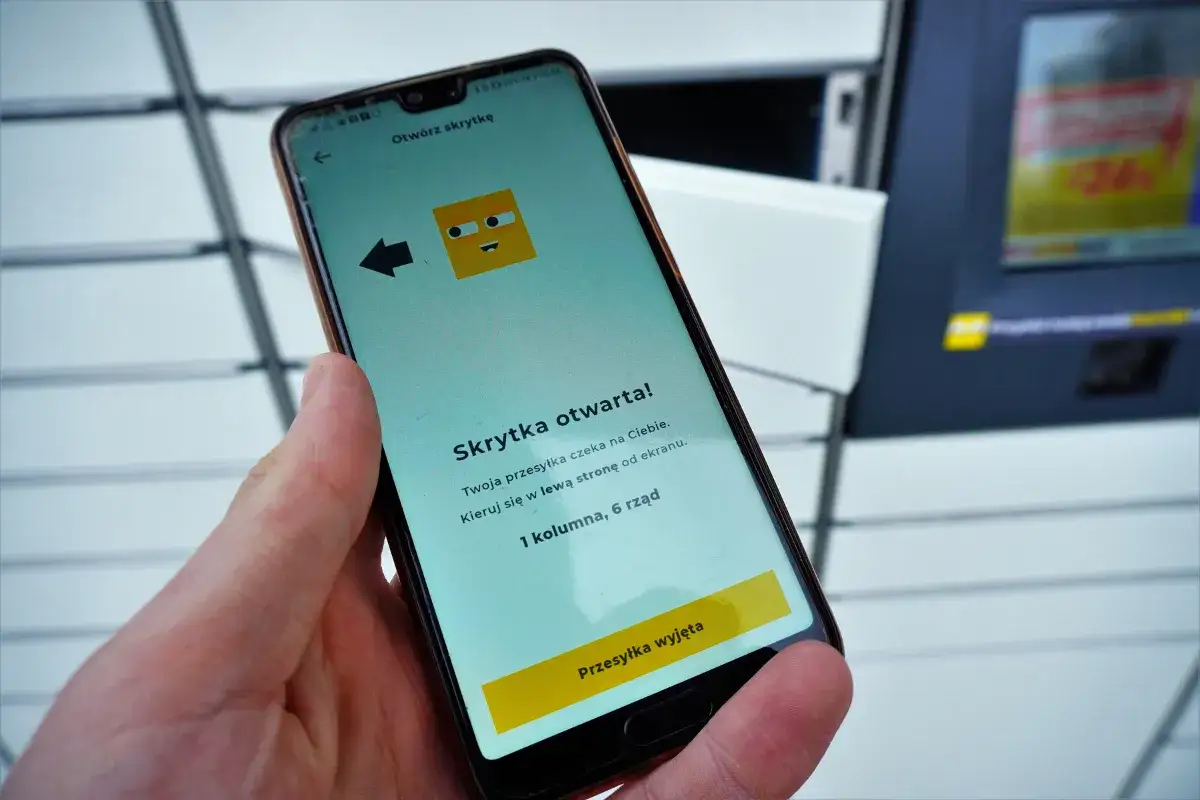 Dłoń trzyma smartfon z aplikacją InPost informującą o otwartej skrytce.