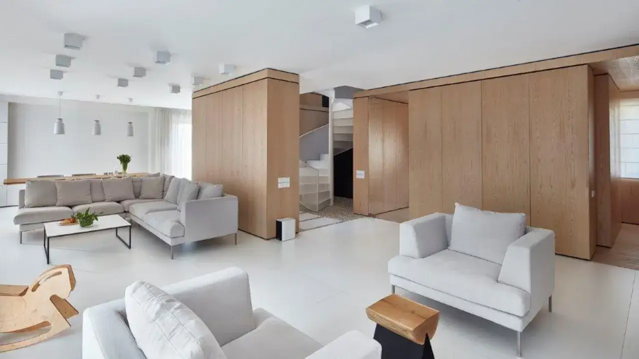 Nowoczesny salon w drewnie i bieli. Jasne ściany, drewniane panele i wygodne sofy tworzą przytulną przestrzeń.