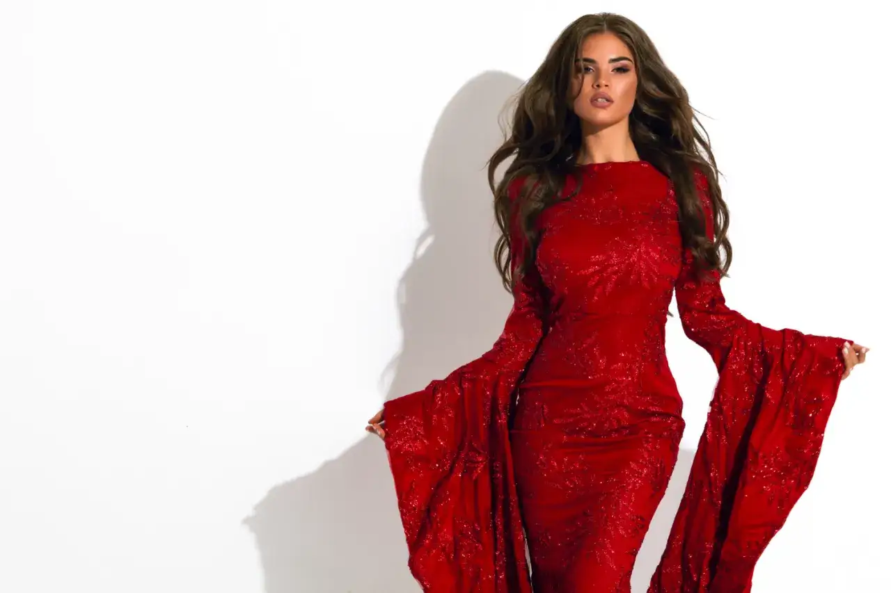Kobieta w czerwonej, błyszczącej sukni z szerokimi rękawami. Inspiracja Moulin Rouge: jak się ubrać na wieczór pełen magii.