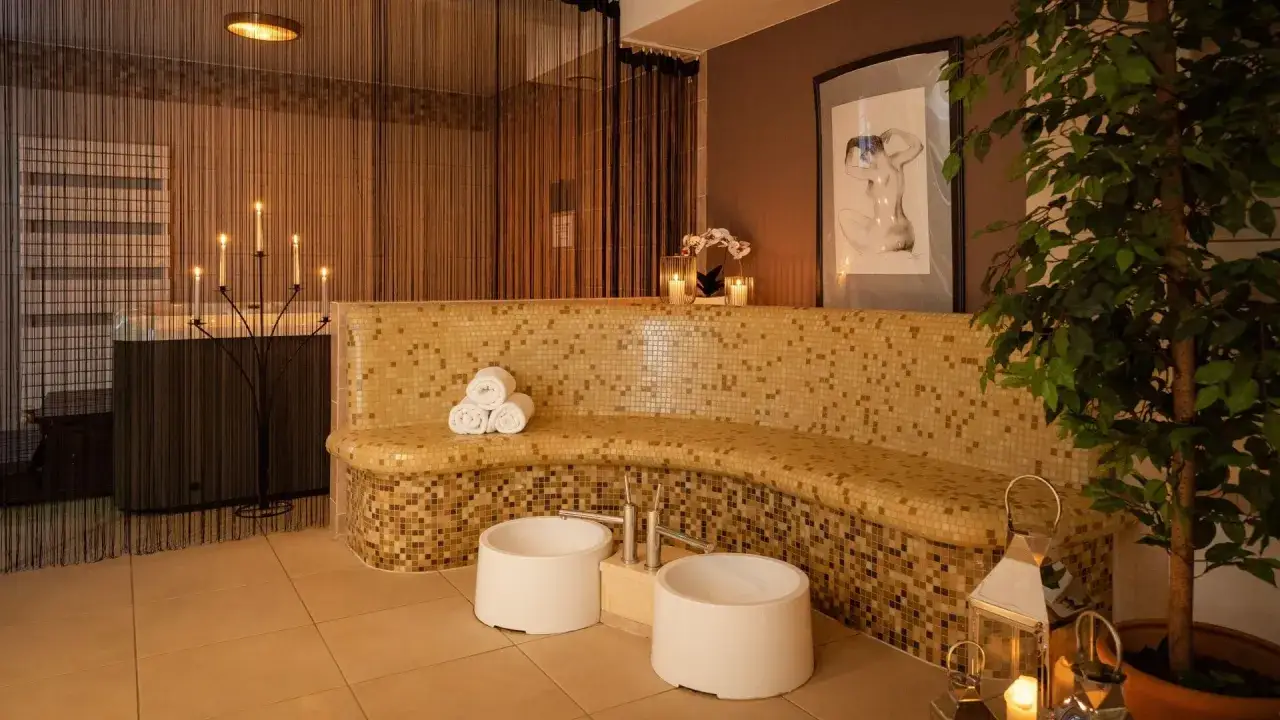 Relaks w spa: mozaikowa ławka, świece, wanna i rośliny tworzą atmosferę spokoju.