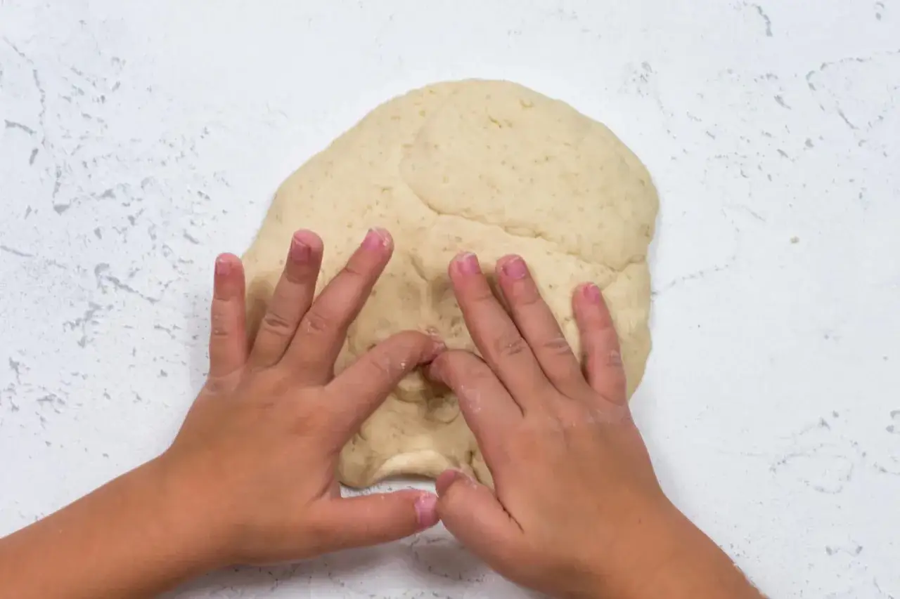 Dziecko ugniata masę solną, ucząc się, jak się robi masę solną.