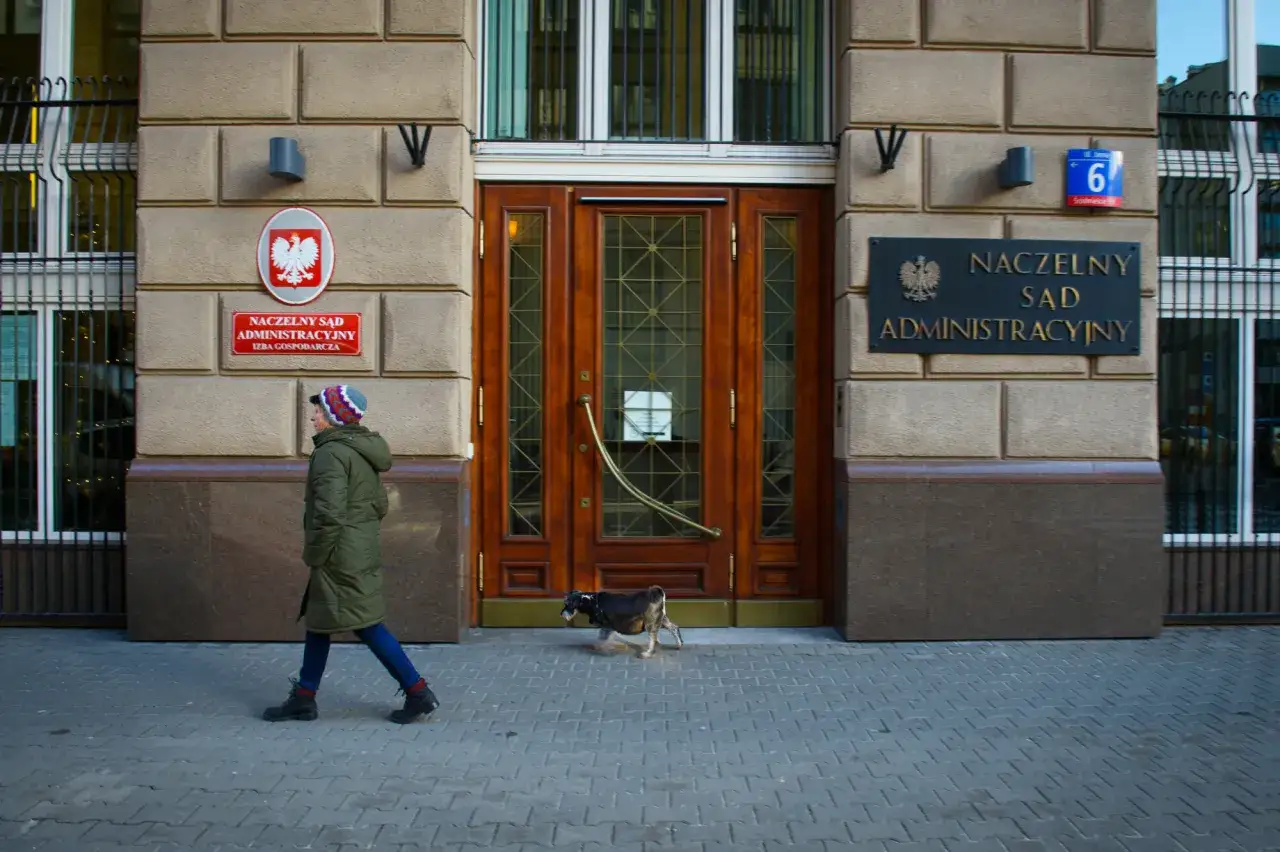 Przed budynkiem Naczelnego Sądu Administracyjnego przechadza się kobieta z psem.