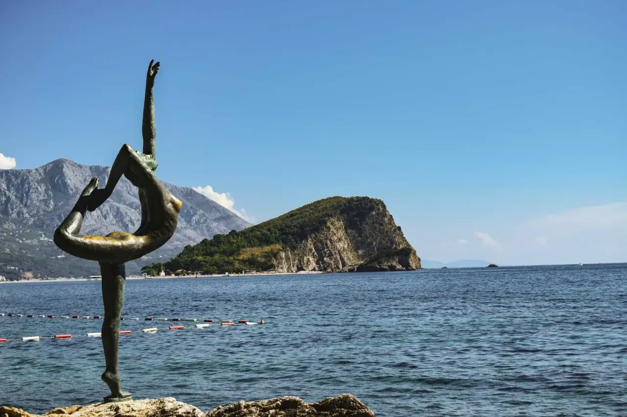 Posąg tancerki na tle gór i morza, idealne miejsce na balkan trip.
