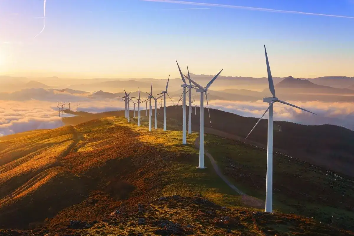 Wiatraki na wzgórzu o zachodzie słońca. Widać, jak działa turbina wiatrowa, łapiąc energię z wiatru.