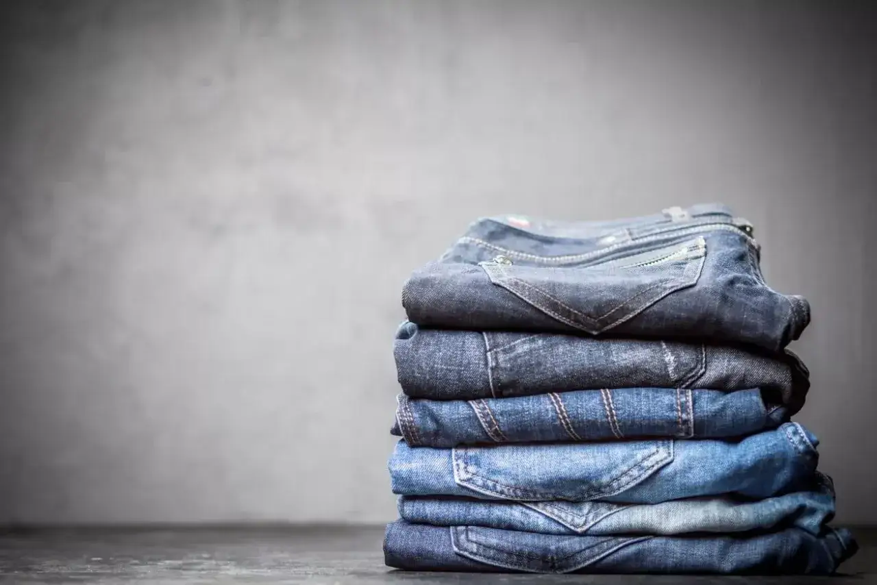 Stosik dekatyzowanych jeansów w różnych odcieniach niebieskiego, z widocznymi kieszeniami i szwami.