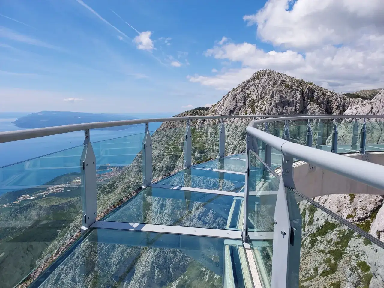 Szklana platforma widokowa z metalową balustradą, z której roztacza się zapierający dech w piersiach widok na morze i góry. To idealne miejsce na spacer po makarska trasa.