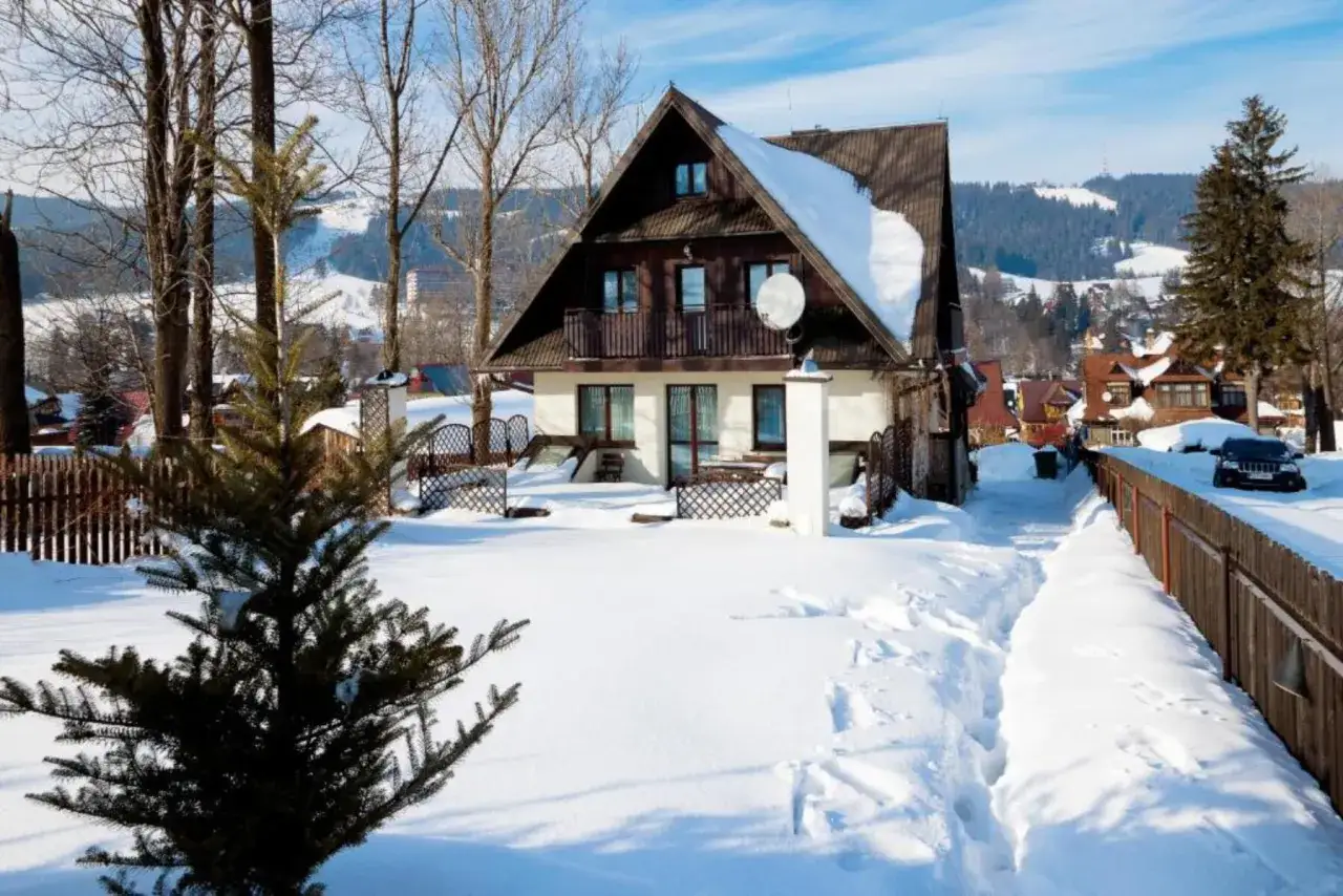 Zimowy krajobraz z willą Wierchy w Zakopanem. Śnieg pokrywa dach i otoczenie, tworząc malowniczą, górską scenerię.