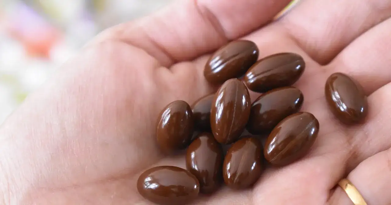 Garść brązowych kapsułek na dłoni. Zastanawiasz się, czy można brać żelazo na noc?