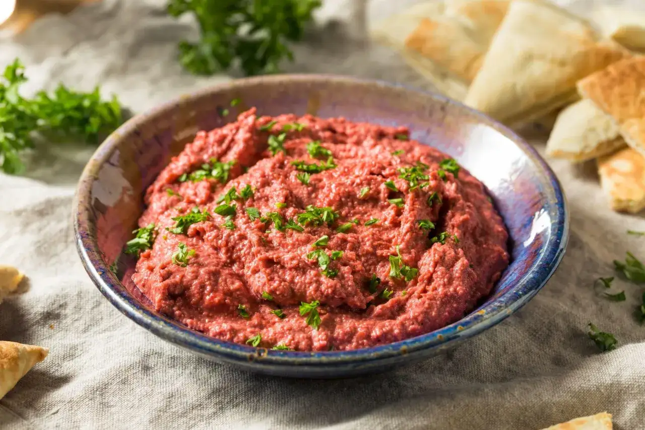 Pyszna pasta z czerwonej fasoli, posypana natką pietruszki, podana z kawałkami pity.