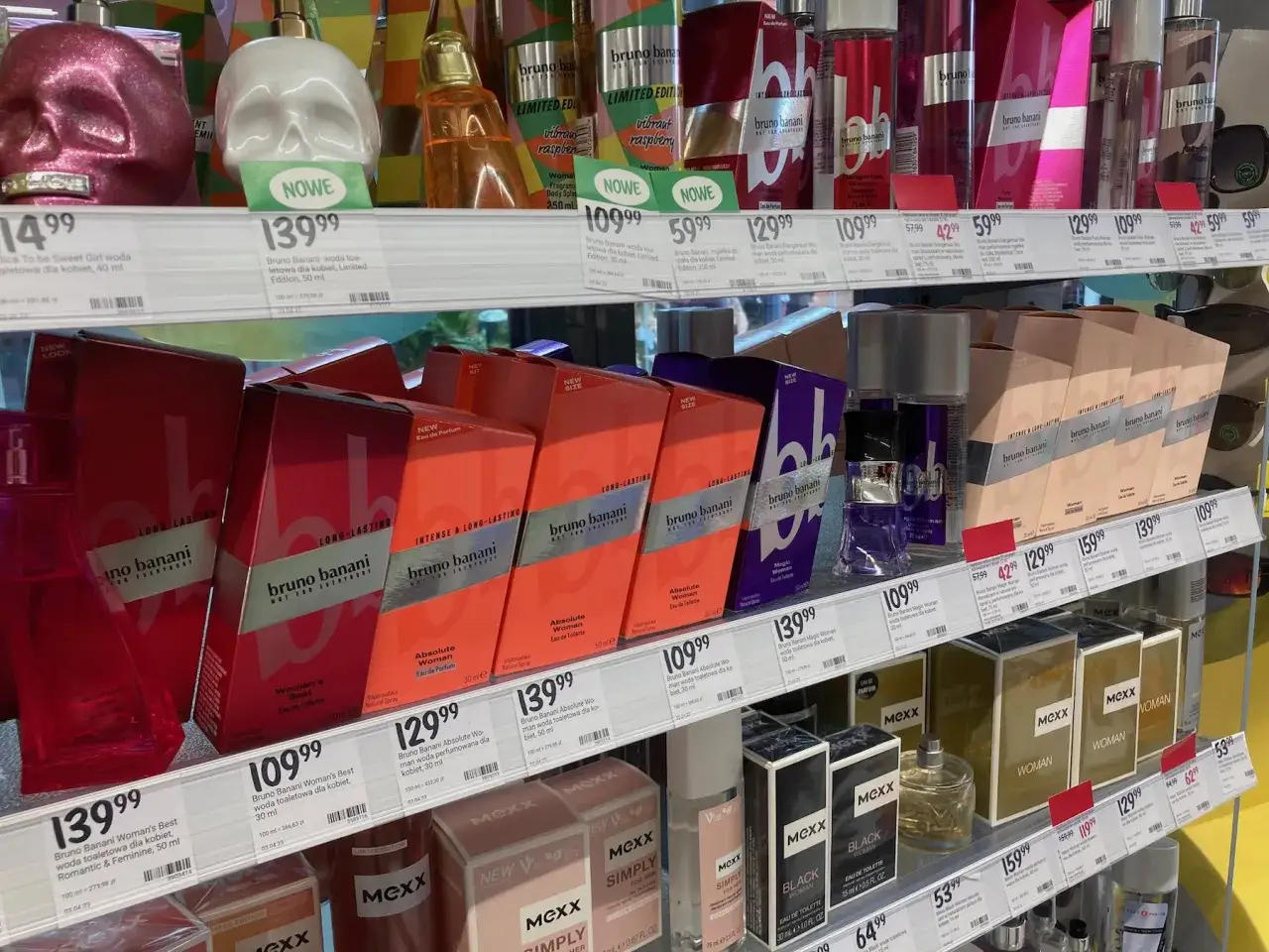 Półki z perfumami w drogerii, w tym flakony w kształcie czaszek i pudełka z marką Bruno Banani.