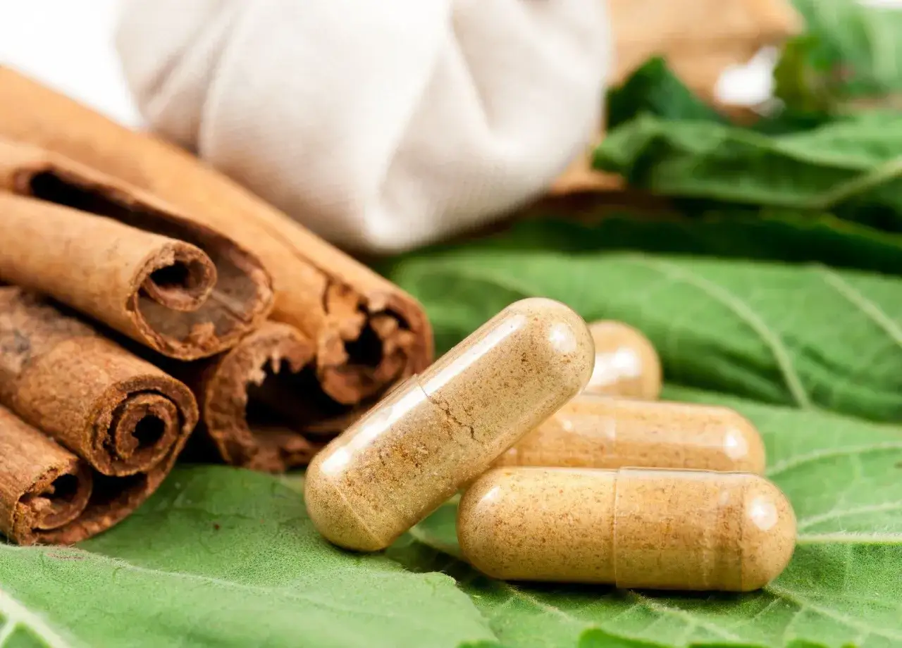 Cynamon na co pomaga? Na zdrowie! Laski cynamonu i kapsułki na zielonych liściach sugerują naturalne wsparcie dla organizmu.