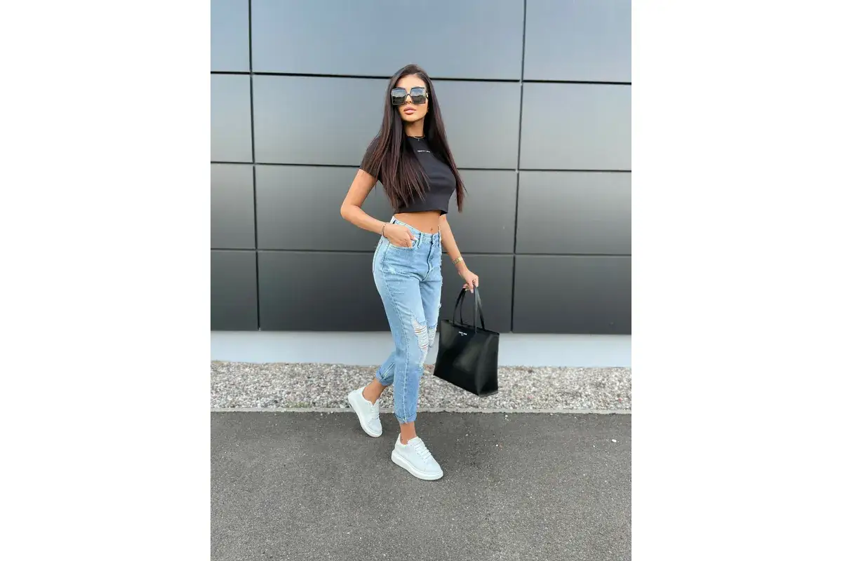 Krótki czarny top i podarte jeansy to świetny przykład, jak łączyć ubrania w zestawy. Dodaj białe sneakersy i czarną torbę.