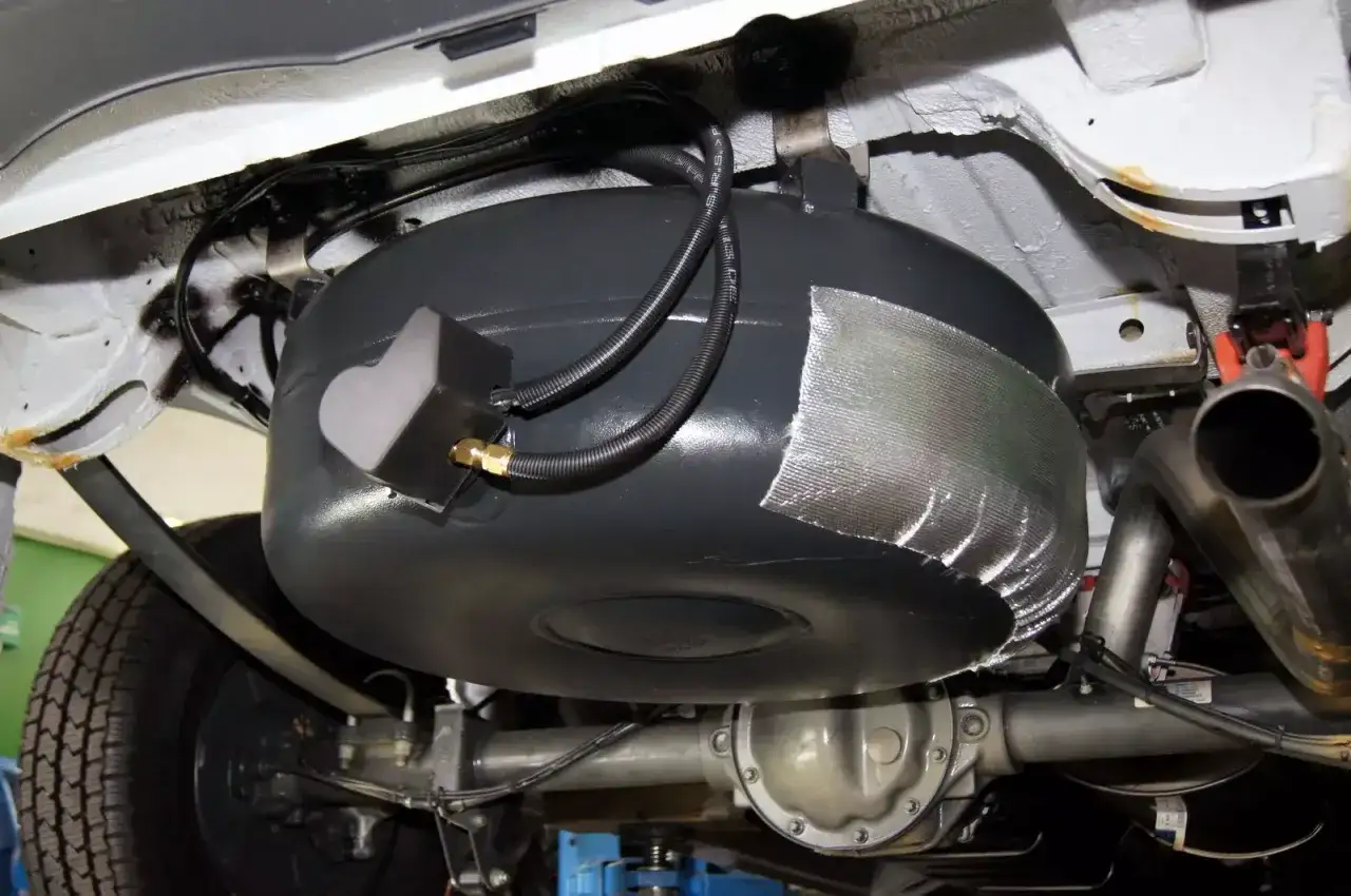 Zbiornik LPG zamontowany pod podwoziem samochodu, widoczna instalacja i elementy wydechu.