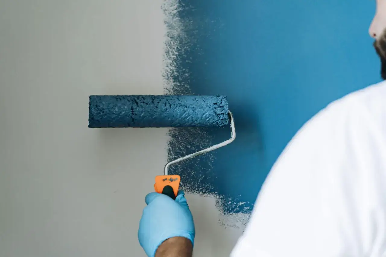 Malowanie ściany wałkiem na niebiesko.