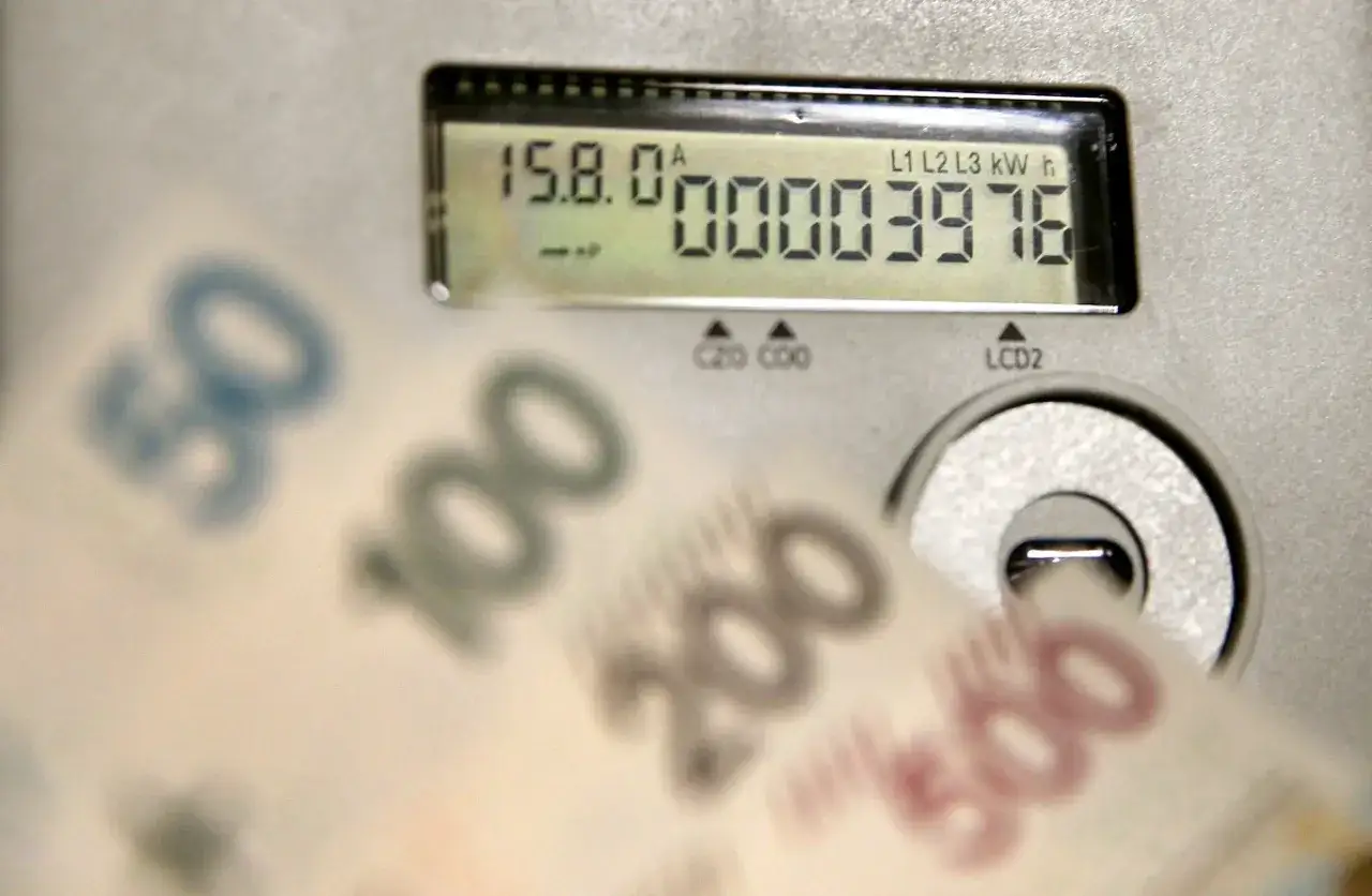 Liczniki energii PGE pokazują zużycie, a banknoty symbolizują opłatę sieciową.