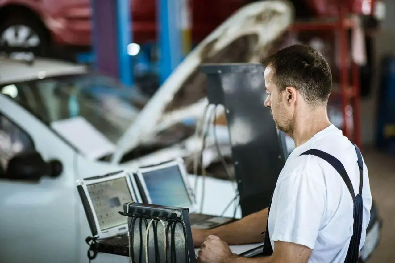 Mechanik sprawdza elektrozawór LPG za pomocą komputerów diagnostycznych w warsztacie samochodowym.