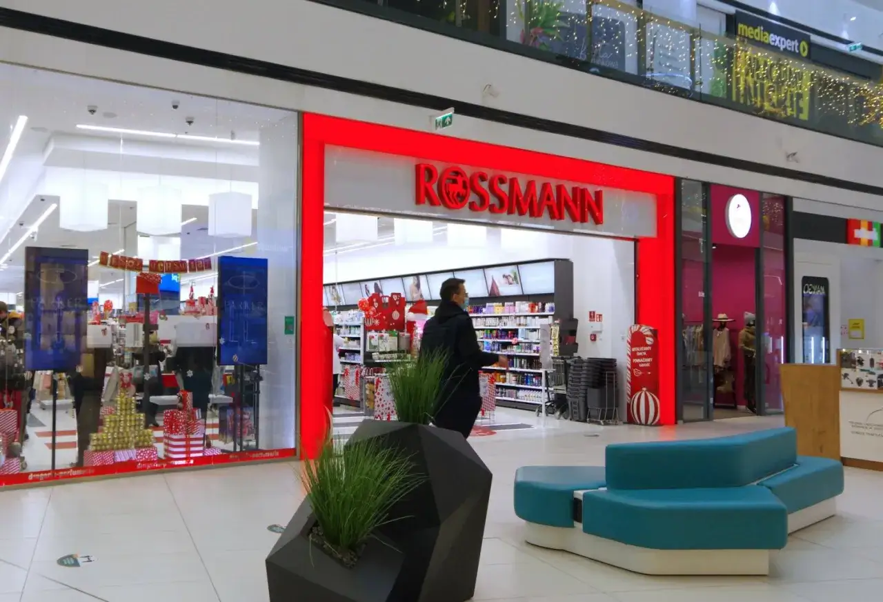 Wejście do drogerii Rossmann w centrum handlowym, z widocznymi promocjami i wystrojem świątecznym.