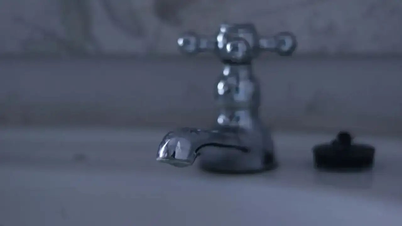 Chromowany kran w łazience, obok korek. Dowiedz się, jak wymienić wylewkę w kranie, by naprawić cieknącą baterię.