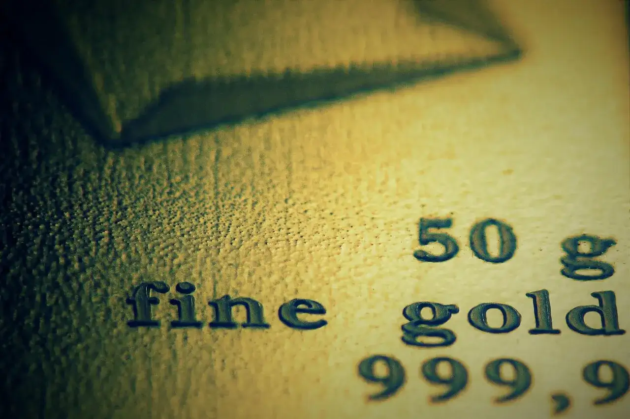 Zbliżenie na tekst "fine gold 50 g 999,9" wybity na powierzchni złota.