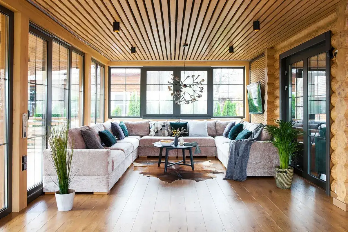 Przytulny salon z narożną sofą i imponującym, drewnianym sufitem.