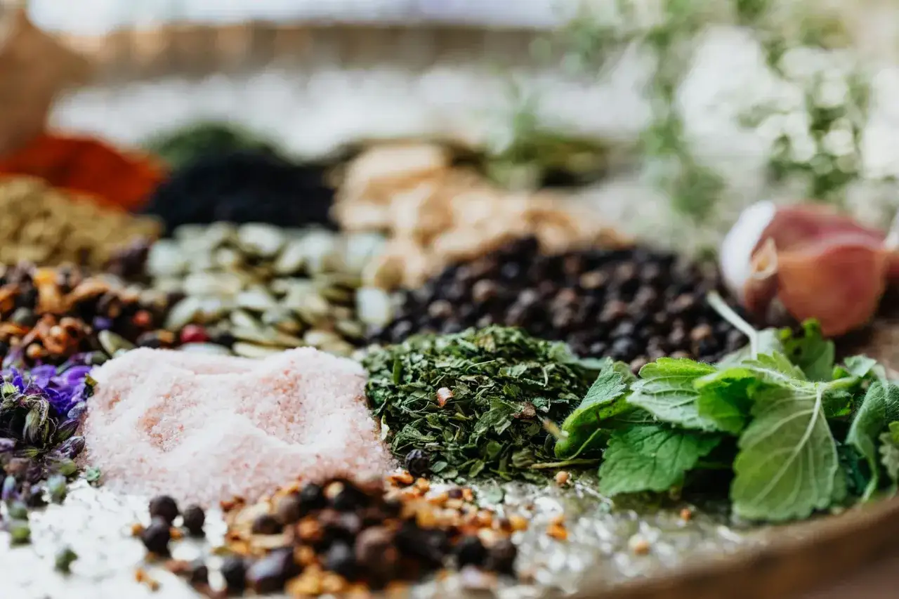 Zbliżenie na różową sól, suszone zioła, pieprz i inne przyprawy.