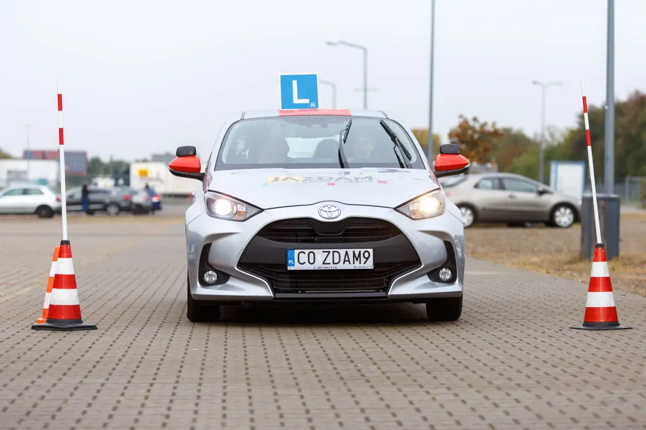 Samochód nauki jazdy z literą "L" na dachu i tablicą "CO ZDAM9". Czy po zdaniu egzaminu na prawo jazdy można jeździć samochodem?