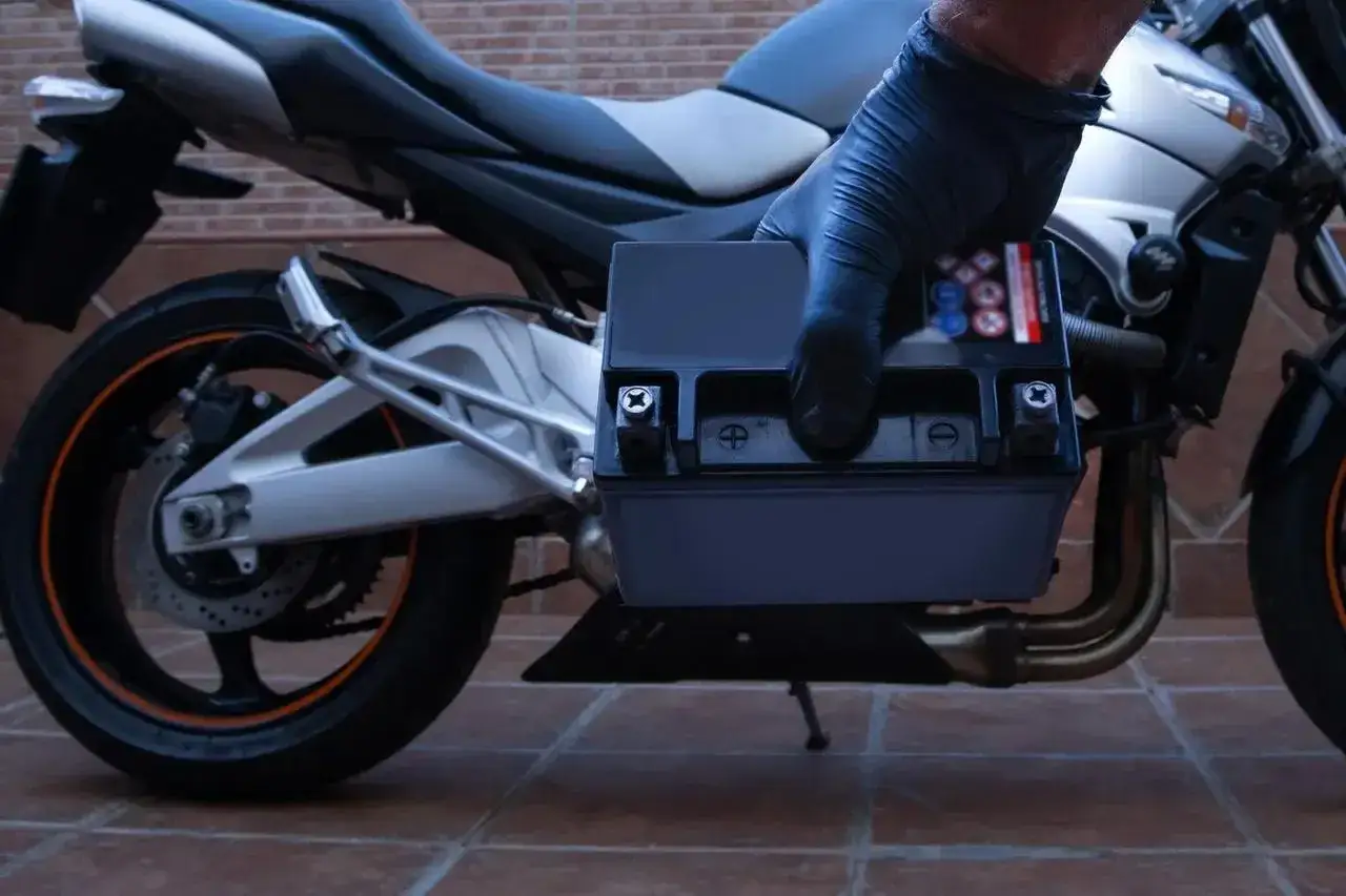 Rękawiczka zakłada nowy akumulator do motocykla. Zastanawiasz się, jaki akumulator do motocykla będzie najlepszy?