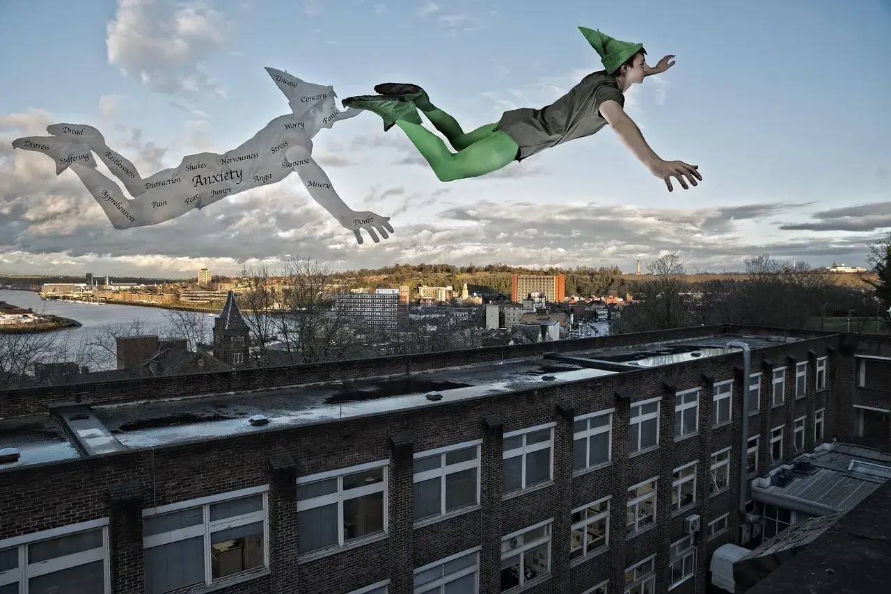 Chłopiec w stroju Piotrusia Pana leci, a za nim unosi się jego cień z napisem "Anxiety" i słowami o lękach.
