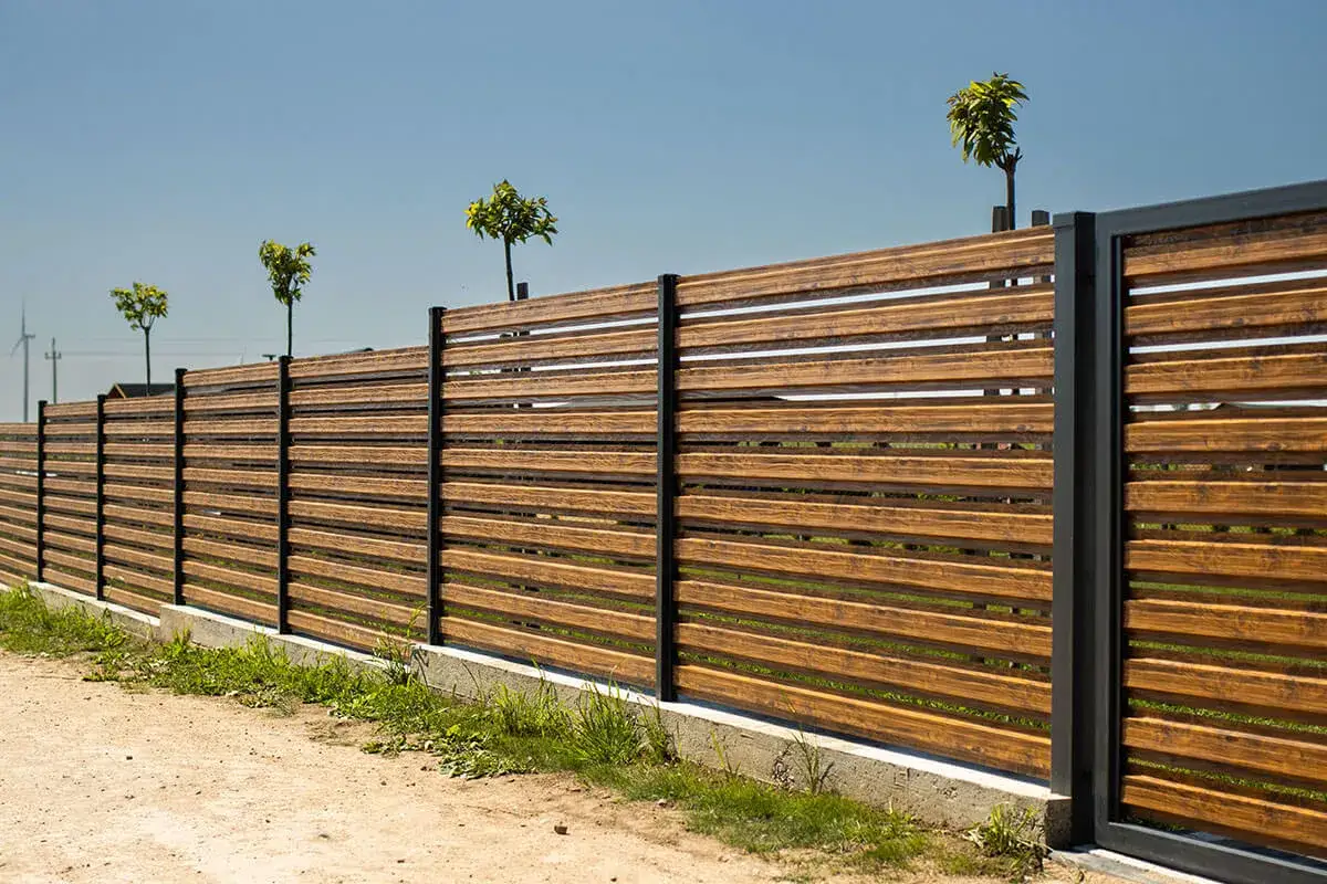 Nowoczesne, drewniane ogrodzenie z czarnymi słupkami. Ciekawe ogrodzenia galeria inspiracji.