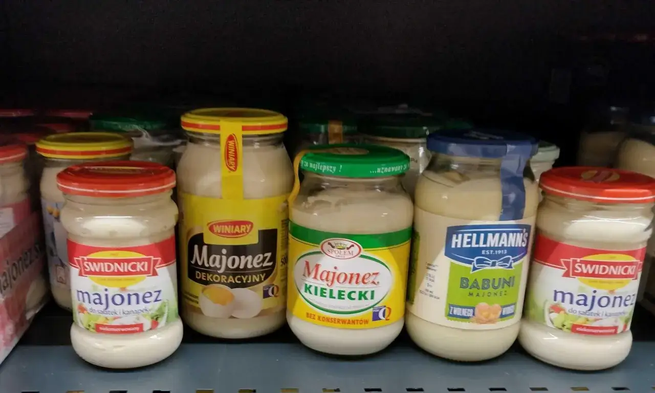 Słoiki z majonezem na półce sklepowej. Widać m.in. majonez Kielecki, Winiary, Świdnicki. Gdzie kupić majonez kielecki roślinny? Tutaj!