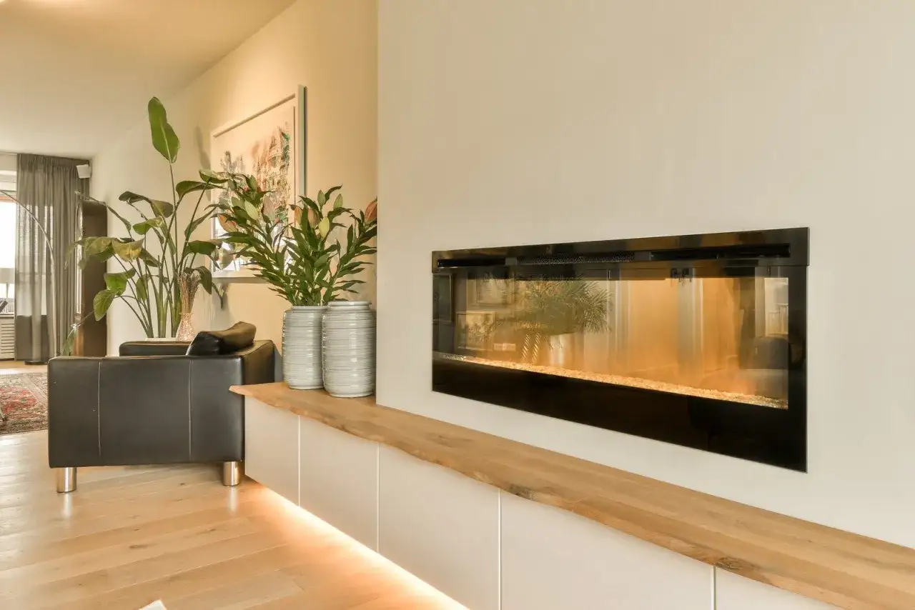 Nowoczesny salon z kominkiem, który można ozdobić, dodając rośliny i wazony. Drewniana półka nad szafkami podkreśla ciepło wnętrza.